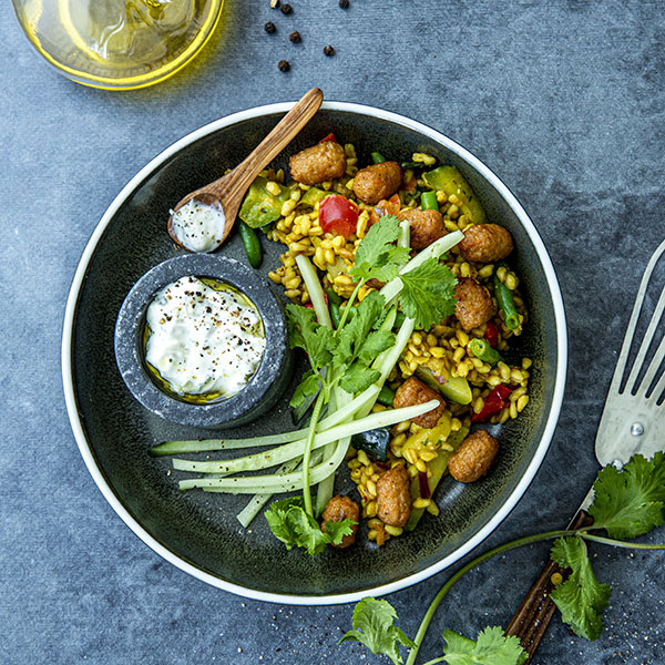 Hvetekornspilaff med grønnsaker, mini blouletter, agurk og tzatziki, servert i en bolle pyntet med mynteblader